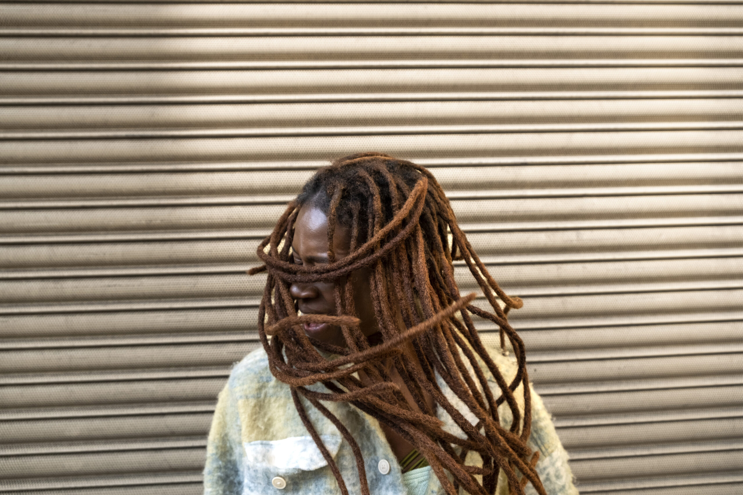 portrait young woman with afro dreadlocks showing off her hair while city